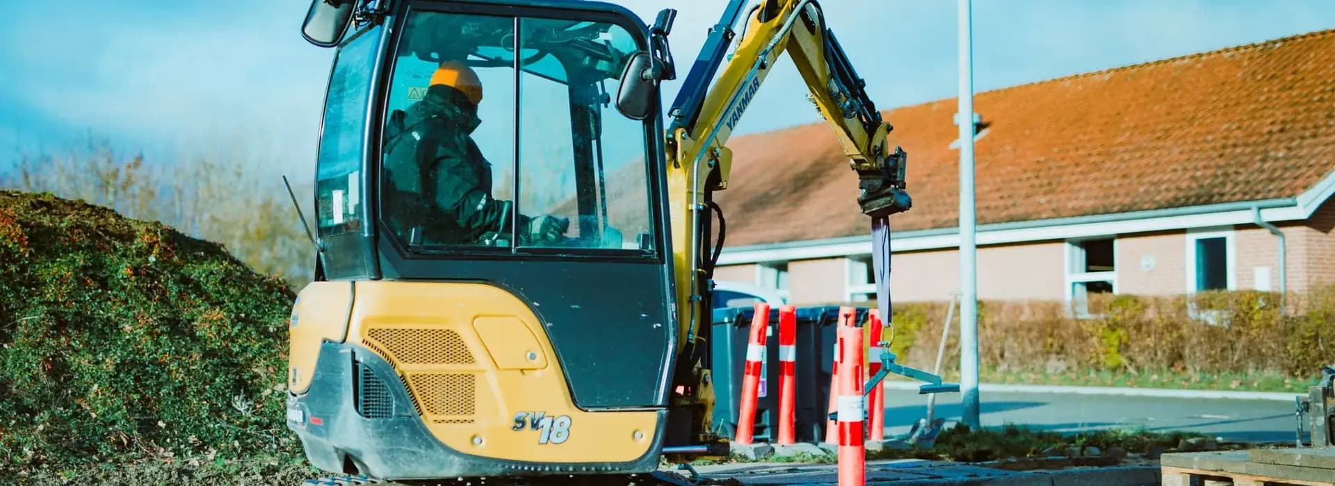Mini excavator working on a site next to houses