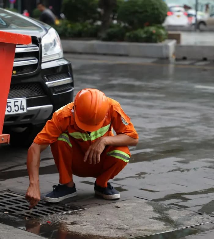 Drainage engineer checking a road gully drain