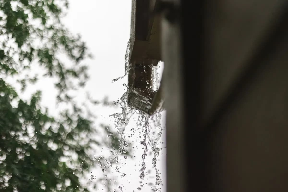 Rainwater spilling over the edge of an overflowing gutter