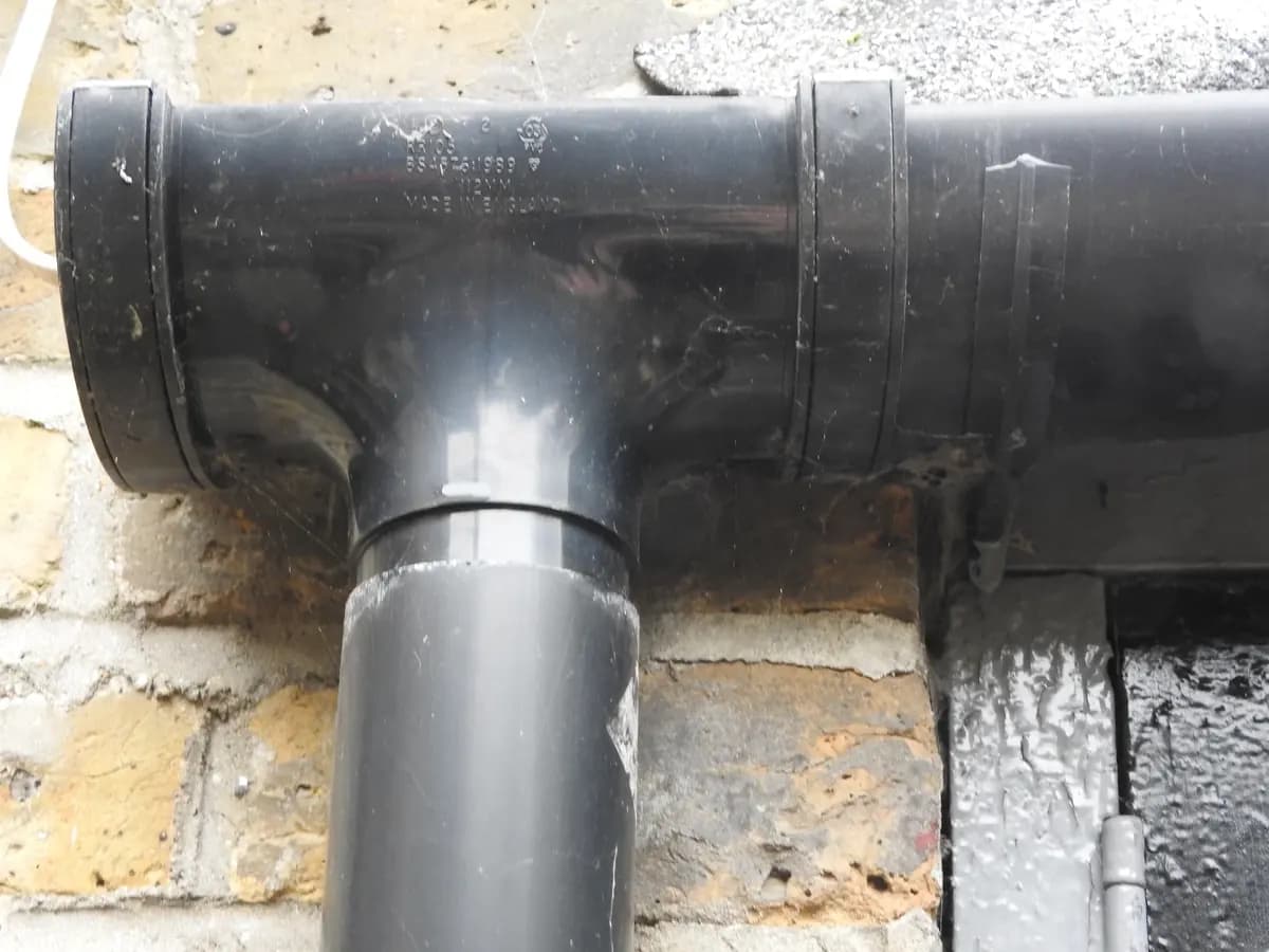 Black uPVC downpipe on a brick wall