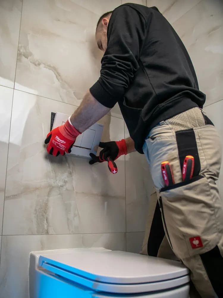 Plumber repairing waste pipework under a sink